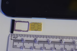 Eine Nano-SIM-Karte mit ihrem Einschub neben einem Lineal als Größenreferenz